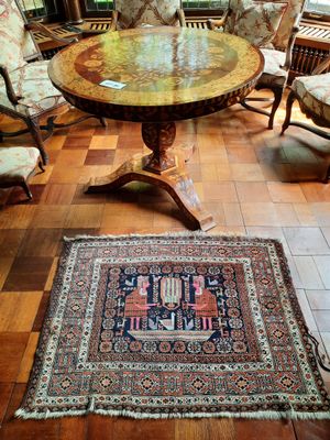 un tapis posé à même le sol dans une pièce où se trouvent des chaises et une table