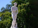 a statue of a woman holding a dog in a park