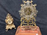 a gold clock on a wooden stand next to two other clocks
