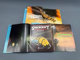 three books of space craft and science fiction on a gray surface