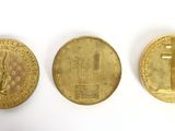 three gold coins sitting next to each other on a white surface