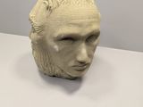 sculpture of a man ' s head on a table with a white background