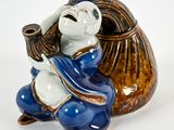 une figurine en céramique représentant un singe tenant un sac