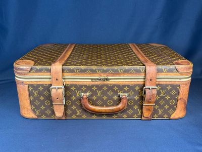 une valise marron et beige posée sur une surface bleue