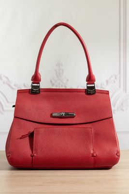un sac à main en cuir rouge posé sur une table en bois