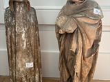 two statues of a man and a woman standing on a wooden floor