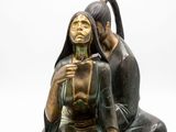 statue of a man and woman sitting on a rock with a bird on their shoulder
