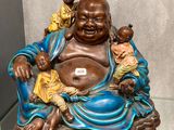 une statue représentant un Bouddha souriant, assis sur une table en verre