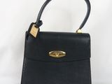 un sac à main en cuir noir avec des ferrures dorées sur la poignée
