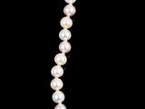 a close up of a pearl necklace on a black background