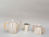 deux théières en argent et une cafetière posées sur une table