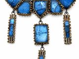 a close up of a necklace with blue stones on a white background