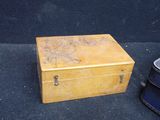 a small wooden box sitting on the ground next to a blue suitcase