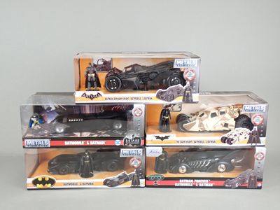three batman action figures and a batmobile in a display case
