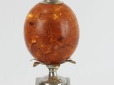 an orange glass lamp with a metal base on a white surface