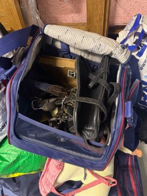 un sac bleu rempli de chaussures et de sacs posé par terre
