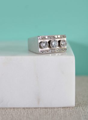 un gros plan d'une bague ornée de trois diamants posée sur un bloc