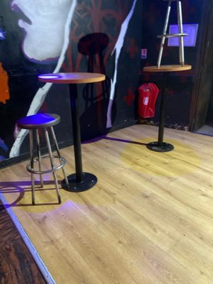 deux tabourets et une table dans une pièce où est accroché un tableau au mur