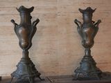 two bronze vases sitting on top of a wooden table