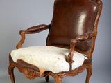 une vieille chaise avec une assise en cuir et un coussin blanc