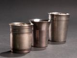 three silver cups are lined up on a black surface