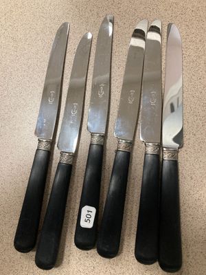 quatre couteaux sont alignés sur un comptoir, avec une étiquette de prix accrochée dessus