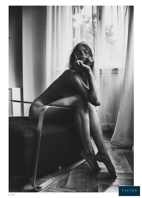 photographie en noir et blanc d'une femme assise sur une chaise devant une fenêtre
