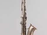 a silver saxophone hanging from a string on the wall