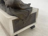 statue of a woman sitting on a bench with her hands on the back of her head