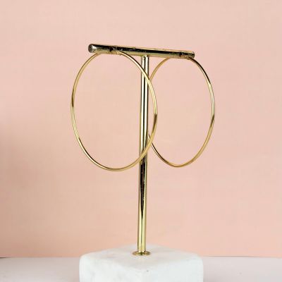a pair of gold hoop earrings sitting on top of a marble stand