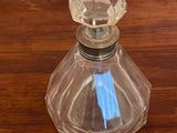 une bouteille en verre contenant un stylo bleu, posée sur une table en bois