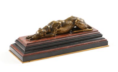 sculpture en bronze représentant un chien couché sur un socle en bois, sur fond blanc