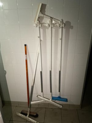 deux balais et une serpillière posés par terre dans la salle de bains