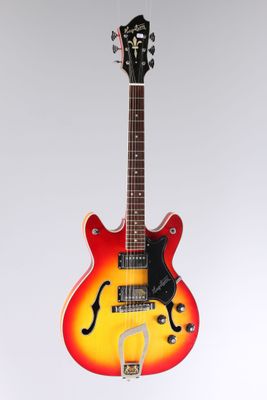 une guitare électrique rouge et jaune posée sur une surface blanche