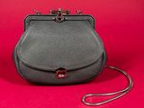 a black leather purse with a metal handle on a red background