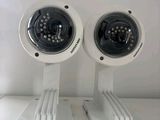 pair of white surveillance cameras mounted to a white wall