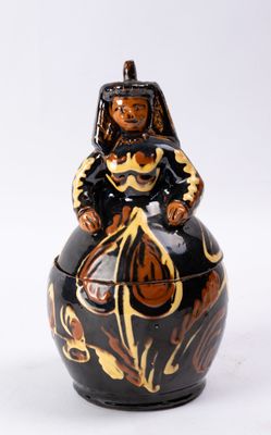 un vase noir et doré sur lequel est assis un homme
