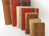 several old books are lined up in a row on a white surface