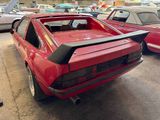 a red car parked in a parking lot with other cars in the background