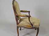 an old chair with a yellow upholstered seat and a wooden frame