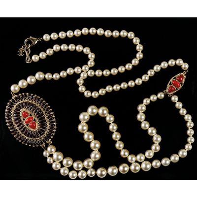 a white pearl necklace with a red stone and silver clasp