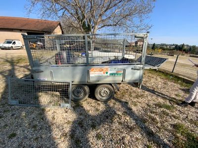 un homme debout à côté d'une remorque équipée d'une cage à l'arrière