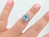 someone is holding a ring with a blue stone on it