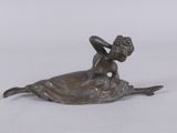 bronze figurine of a woman laying on her stomach