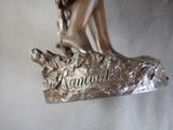 a bronze statue of a woman sitting on a tree branch