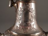 a silver tea pot with a handle on a table