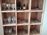 a wooden shelf with wine glasses and bottles on it