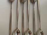 six spoons and a spoon rest on a white surface