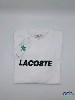 un t-shirt Lacoste blanc avec un logo Lacoste noir sur le devant