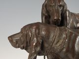 bronze statue of two dogs on a rock with a white background